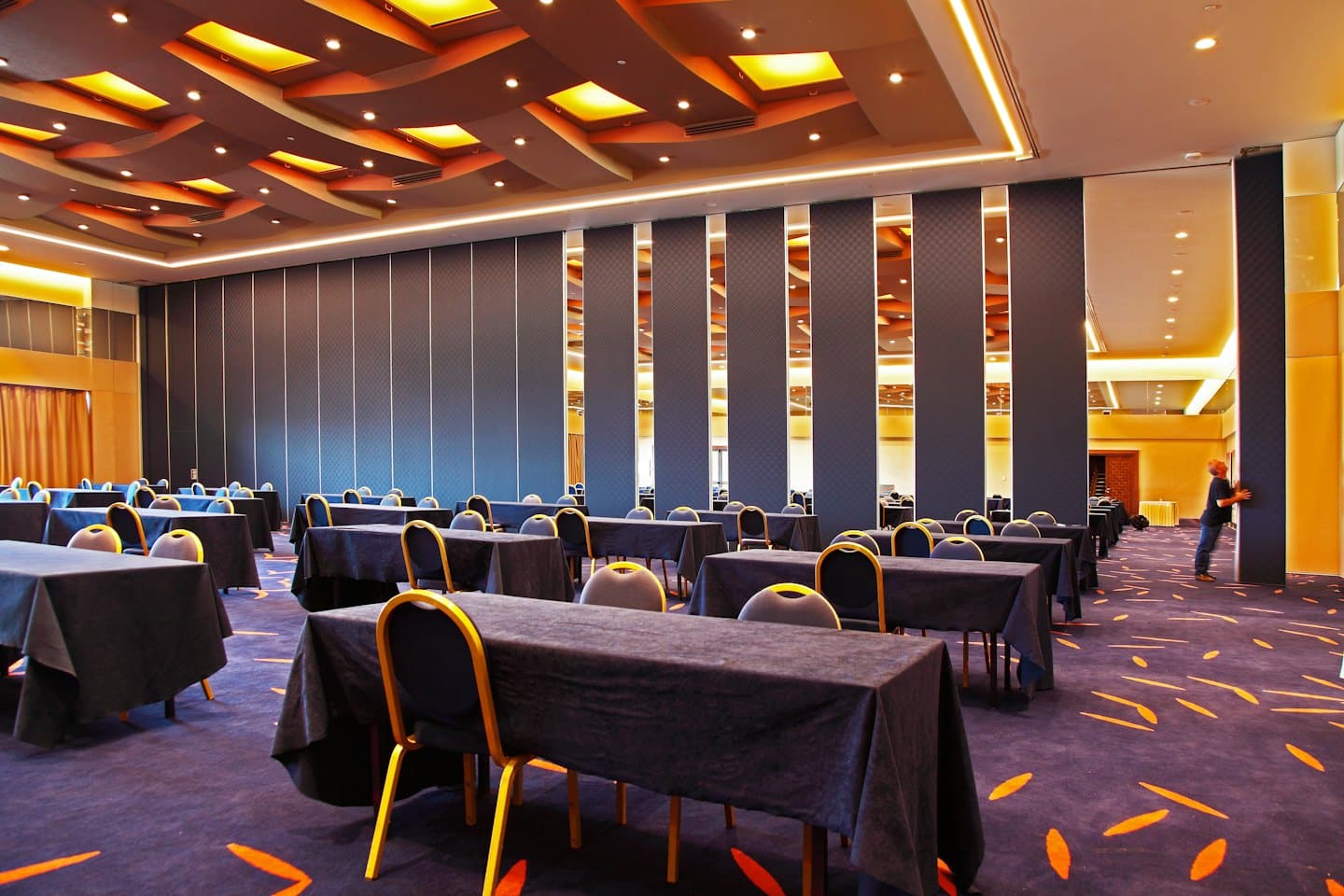 A person adjusts a partition wall in a modern conference room.