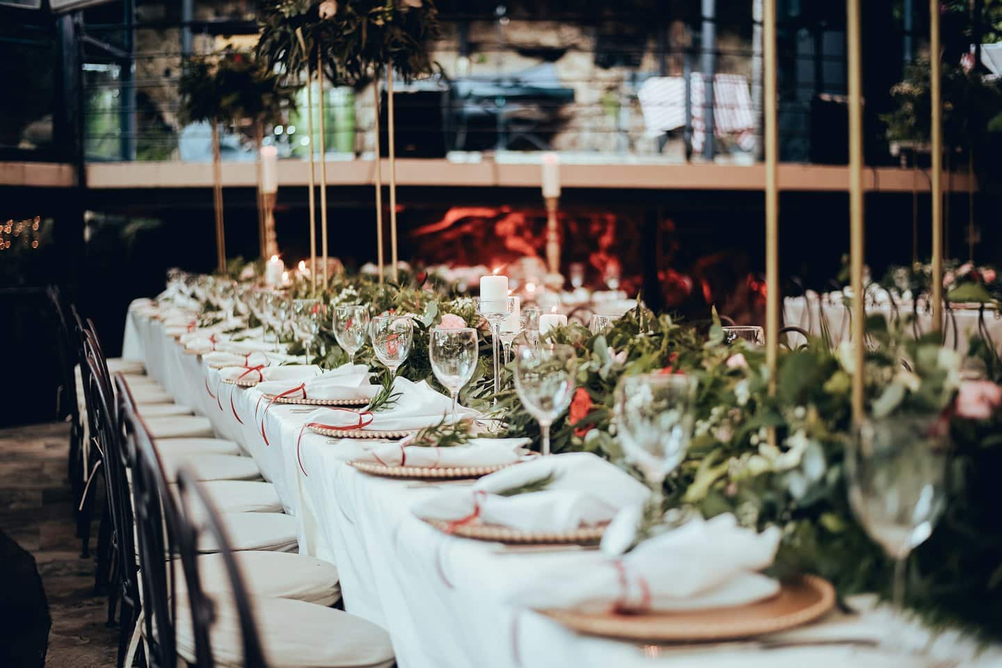 A long dining table set for a formal event with candles and floral garland.